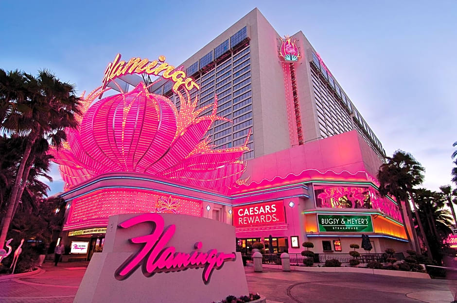 Brightly lit hotel and casino with neon signs and palm trees.